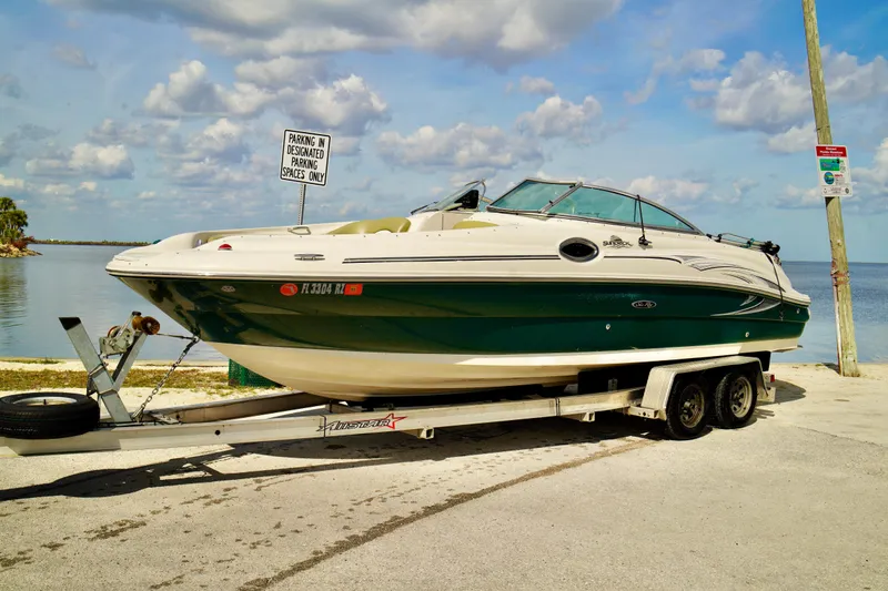 Slide: The Image of 2005 Sea Ray 240 Bow Rider on trailer by the water, under a partly cloudy sky. - 3