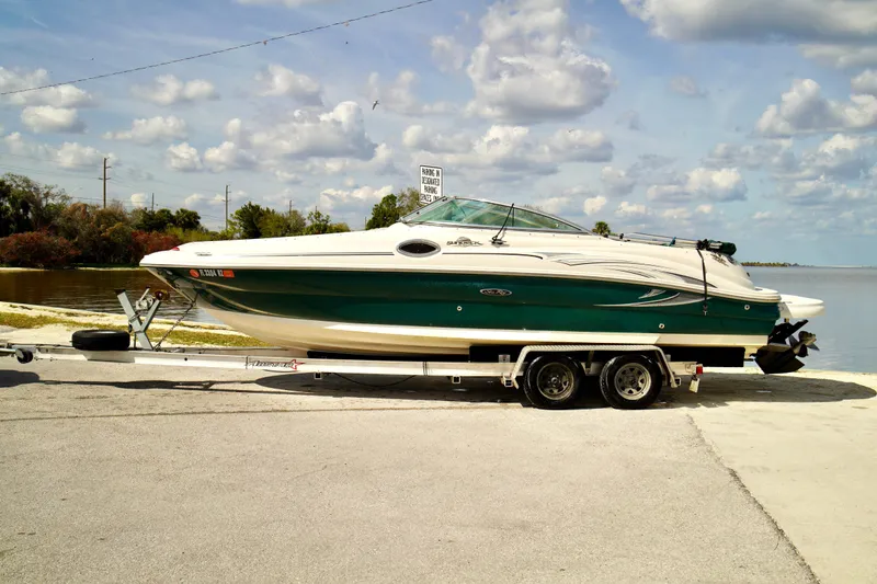 Slide: The Image of 2005 Sea Ray 240 Bow Rider on trailer by a lake under a cloudy sky. - 4