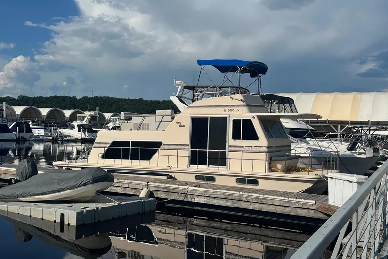 Slide: The Image of 1989 Holiday Mansion Super houseboat docked at a marina under a cloudy sky. - 14