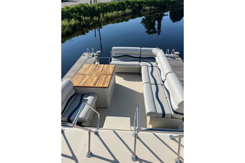 Slide: The Image of 1989 Holiday Mansion Super boat deck with cushioned seating and wooden table by the water. - 3