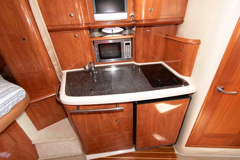 Slide: The Image of 2007 Four Winns 358 Vista yacht kitchen with wood cabinetry, sink, microwave, and stovetop. - 9