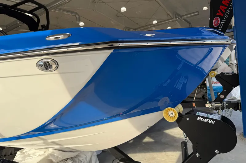 Slide: The Image of 2025 Yamaha Boats 222XE, blue and white hull, displayed indoors on a trailer. - 2
