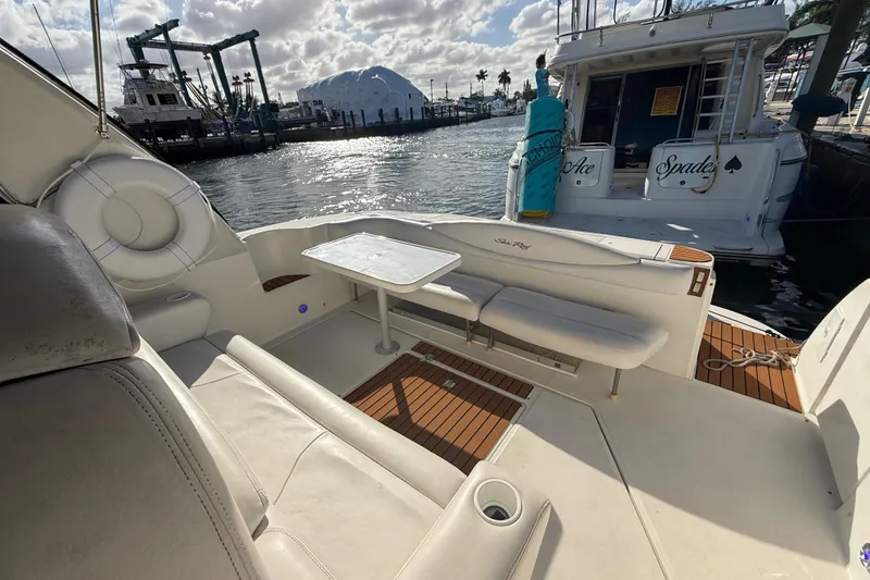Slide: The Image of 1999 Sea Ray 410 Express Cruiser interior with seating and table, docked by the water. - 11