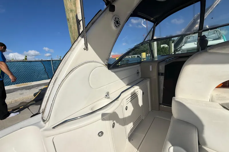 Slide: The Image of 1999 Sea Ray 410 Express Cruiser interior with white seating and cabinetry, docked under blue sky. - 12