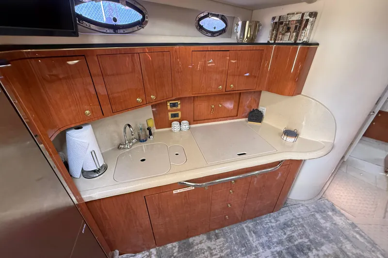 Slide: The Image of 1999 Sea Ray 410 Express Cruiser kitchen with wooden cabinets and countertop. - 19