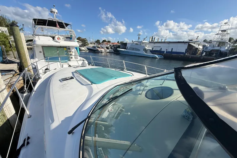 Slide: The Image of 1999 Sea Ray 410 Express Cruiser docked at marina under clear blue sky. - 6