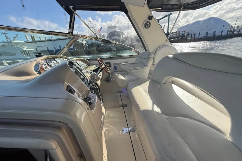 Slide: The Image of 1999 Sea Ray 410 Express Cruiser interior with helm and seating, docked at marina. - 9