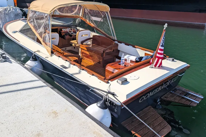 The Image of 1973 Lyman Islander boat docked, featuring a tan canopy and American flag. - 0