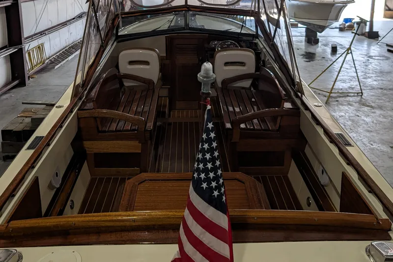 Slide: The Image of 1973 Lyman Islander boat interior with wooden seating and American flag in a storage facility. - 12