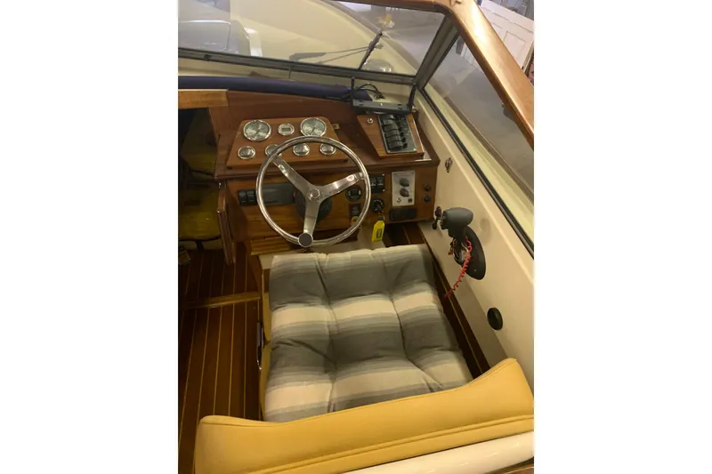 Slide: The Image of 1973 Lyman Islander boat interior with wooden dashboard and striped seat cushion. - 15