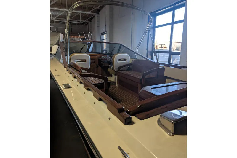 Slide: The Image of 1973 Lyman Islander boat interior with wooden seating and steering wheel in a showroom. - 17