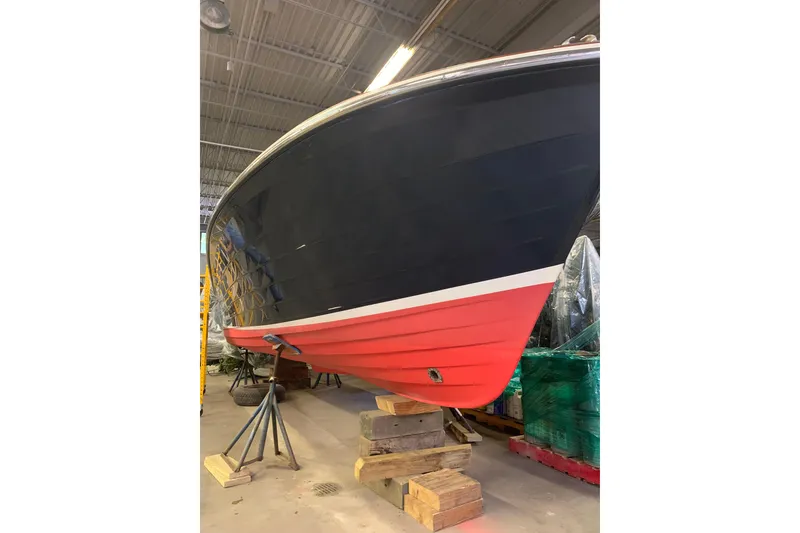 Slide: The Image of 1973 Lyman Islander boat with red and black hull in storage. - 2