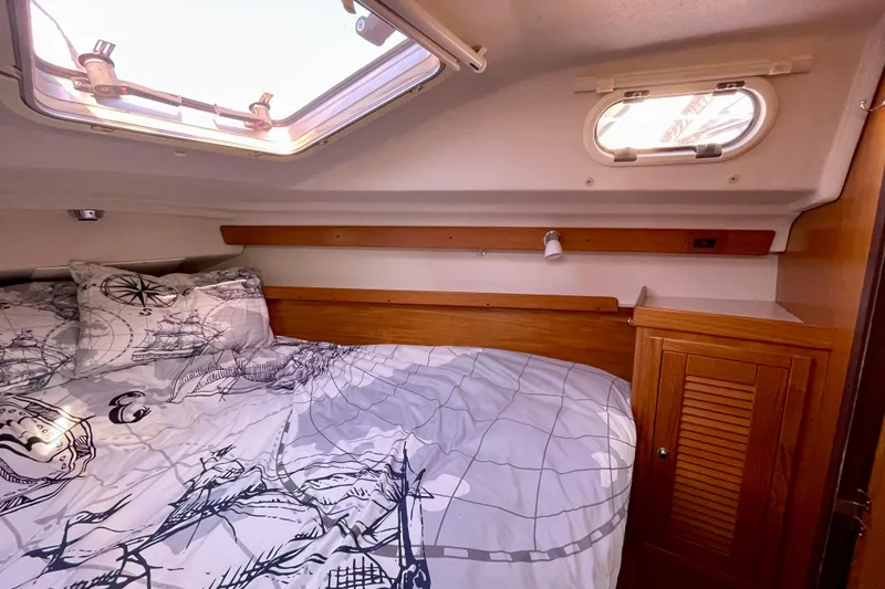 Slide: The Image of Cozy cabin interior of 2004 Catalina 350 sailboat with nautical-themed bedding. - 24