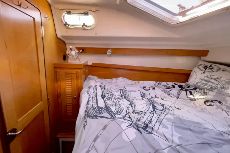 Slide: The Image of Cozy cabin interior of 2004 Catalina 350 sailboat with nautical-themed bedding. - 25
