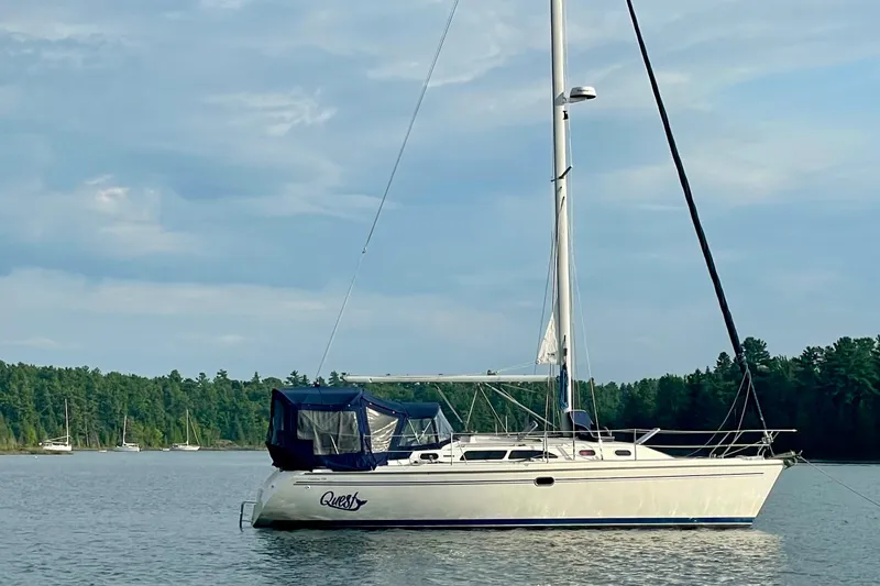 Slide: The Image of 2004 Catalina 350 sailboat anchored on a serene lake with forested shoreline. - 3