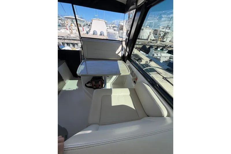 Slide: The Image of Interior of 2023 Boston Whaler 345 Conquest with seating and table, docked at marina. - 11