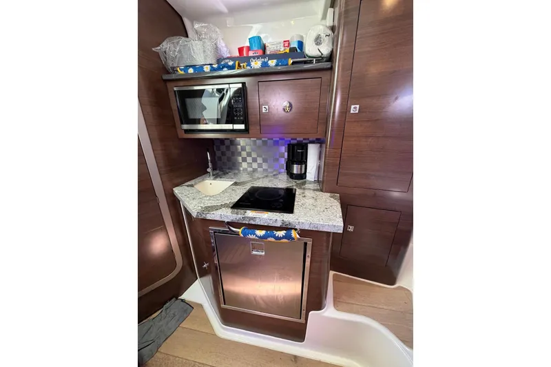Slide: The Image of 2023 Boston Whaler 345 Conquest galley with microwave, sink, and cooktop. - 14