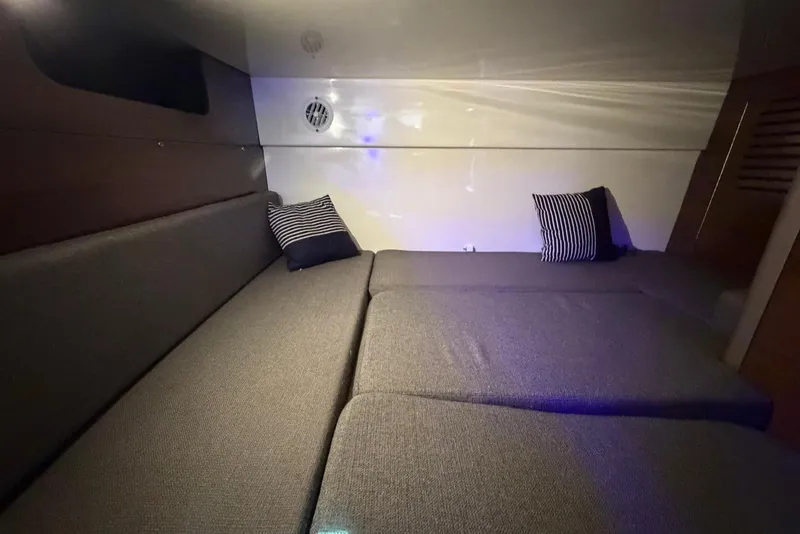 Slide: The Image of 2023 Boston Whaler 345 Conquest cabin interior with striped pillows and cozy seating. - 17