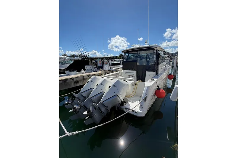 Slide: The Image of 2023 Boston Whaler 345 Conquest docked with triple outboard engines under a clear blue sky. - 3
