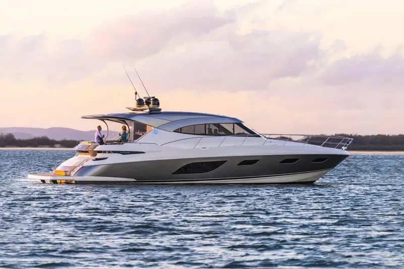 The Image of 2020 Riviera 6000 Motor Yacht cruising on calm waters at sunset. - 0