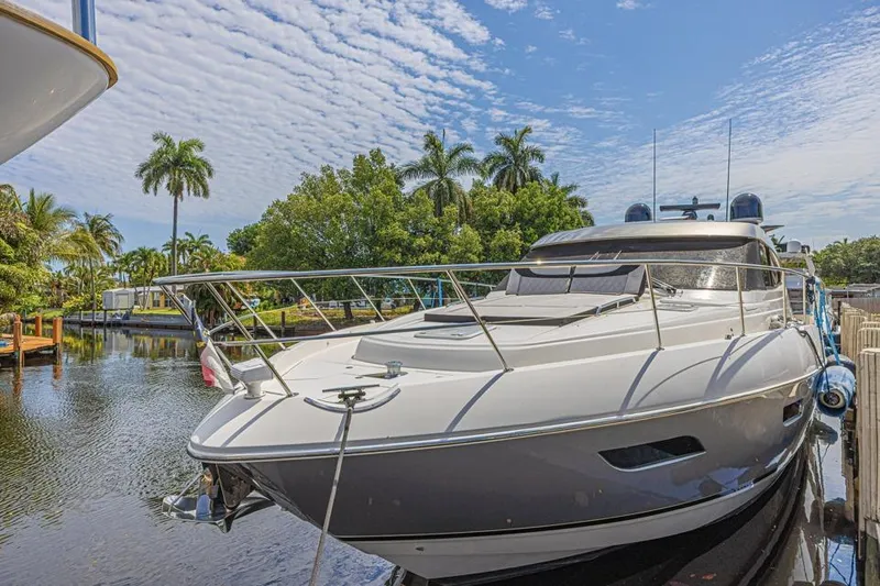 Slide: The Image of 2021 Riviera 6000 Sport Yacht Platinum Edition docked by tropical trees. - 1