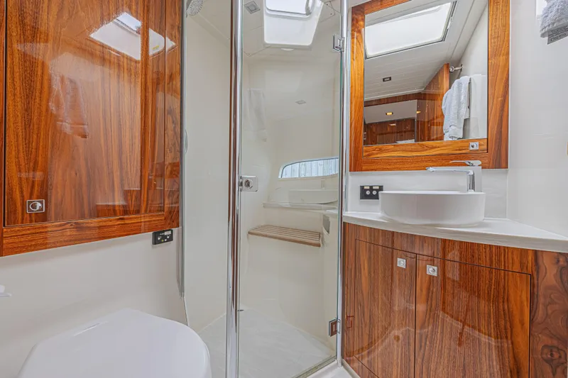 Slide: The Image of Luxurious bathroom in 2021 Riviera 6000 Sport Yacht Platinum Edition with elegant wood finishes. - 13