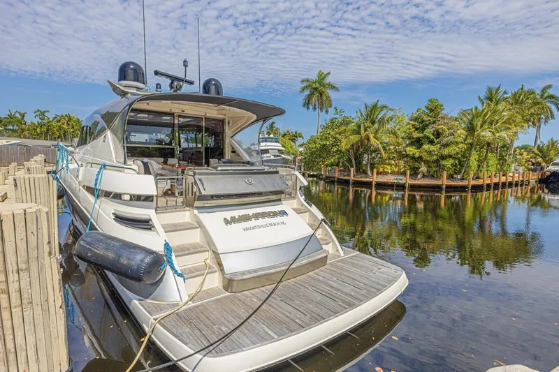 Slide: The Image of 2021 Riviera 6000 Sport Yacht Platinum Edition docked by tropical waterfront. - 3