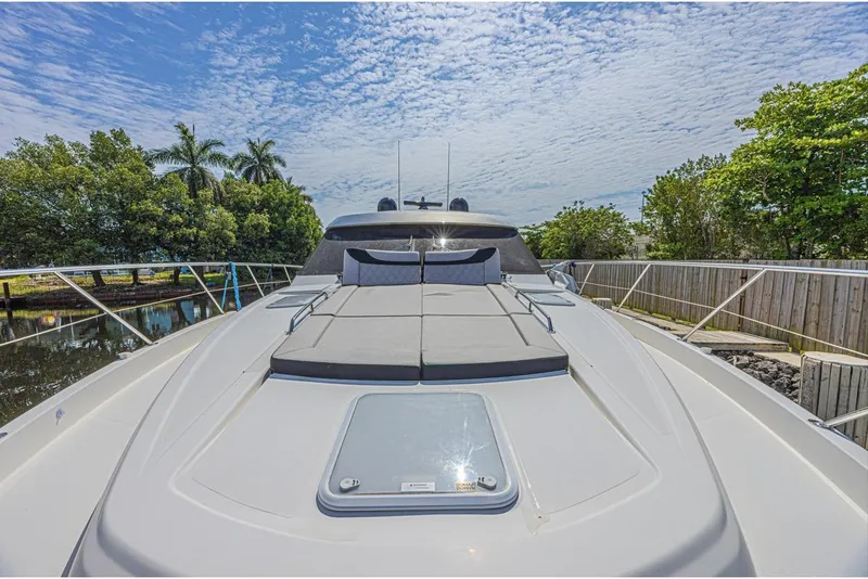 Slide: The Image of 2021 Riviera 6000 Sport Yacht Platinum Edition on a sunny day, docked near lush greenery. - 4