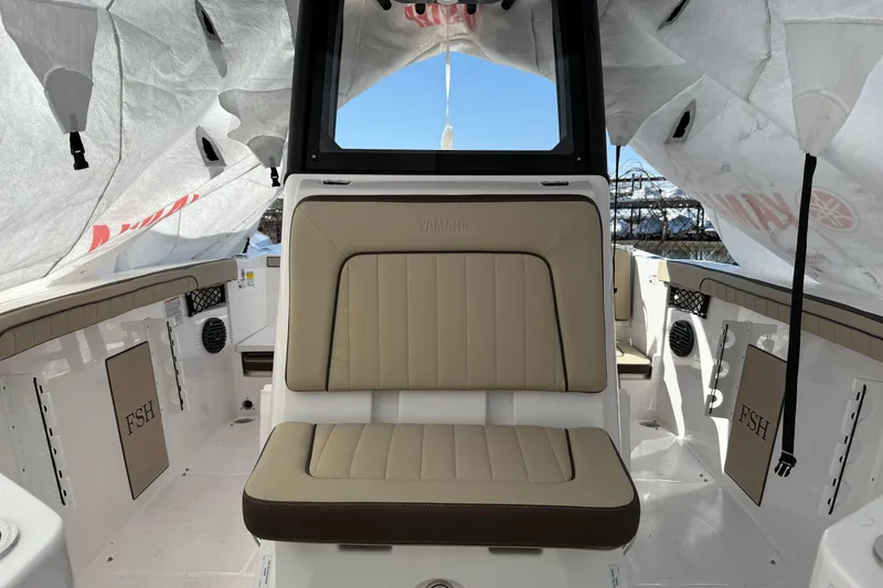 Slide: The Image of 2025 Yamaha Boats 222 FSH Sport E interior with beige seating under protective cover. - 5