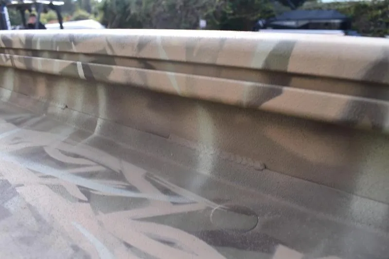 Slide: The Image of Camouflage-patterned side of a 2026 Lowe Roughneck RX1860 Tunnel Jet boat. - 12