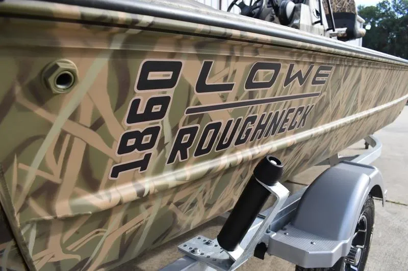 Slide: The Image of 2026 Lowe Roughneck RX1860 Tunnel Jet boat with camouflage design on trailer. - 4