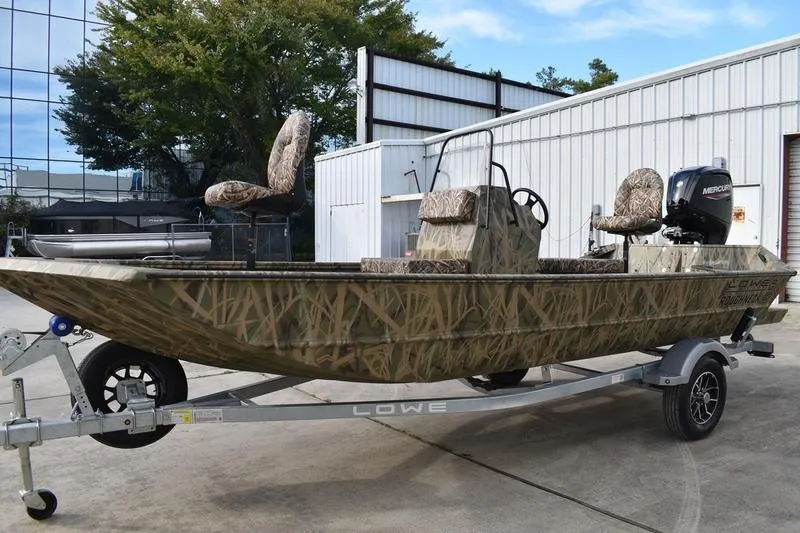Slide: The Image of 2026 Lowe Roughneck RX1860 Tunnel Jet boat on trailer, camo design, parked outdoors. - 9