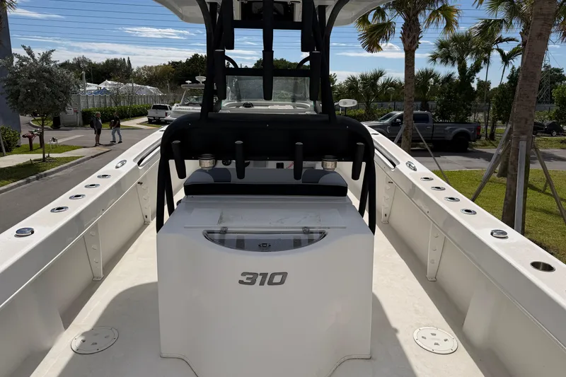 Slide: The Image of 2021 Twin Vee 310 CC GF boat interior with console and seating, surrounded by palm trees. - 11
