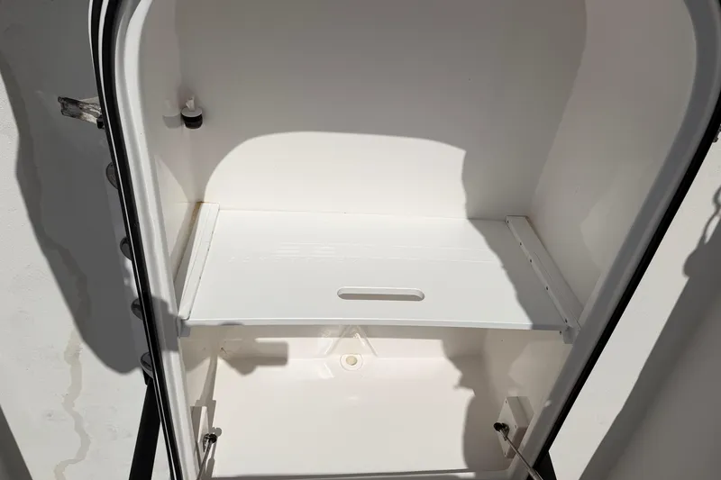 Slide: The Image of Open storage compartment in 2021 Twin Vee 310 CC GF boat, featuring a white interior. - 12