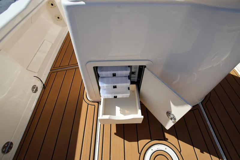 Slide: The Image of 2024 Grady-White 251 Coastal Explorer boat storage compartment with open drawer on teak deck. - 14