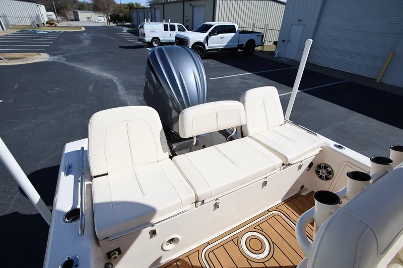 Slide: The Image of 2024 Grady-White 251 Coastal Explorer boat interior with seating and motor, parked outdoors. - 23