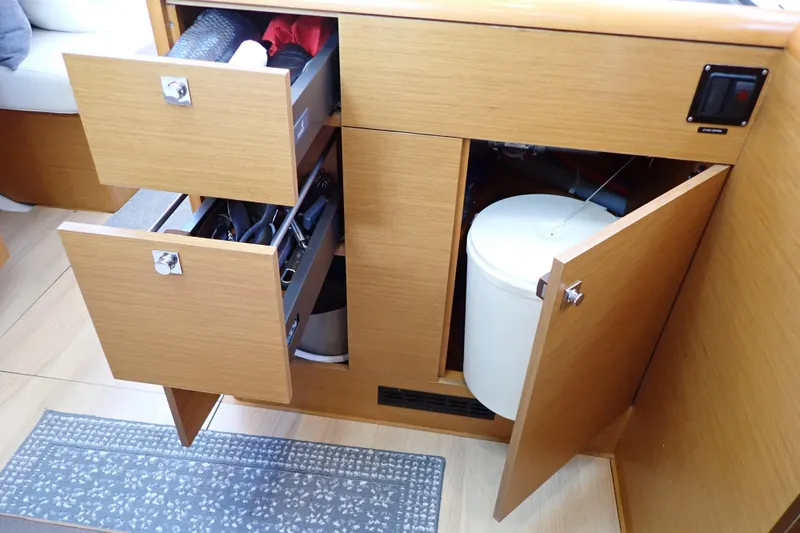 Slide: The Image of Interior of 2018 Jeanneau Sun Odyssey 389 showing open wooden cabinets and drawers. - 110