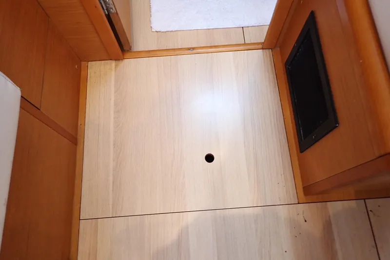 Slide: The Image of Interior flooring of 2018 Jeanneau Sun Odyssey 389 sailboat, featuring wooden panels and a ventilation grate. - 140