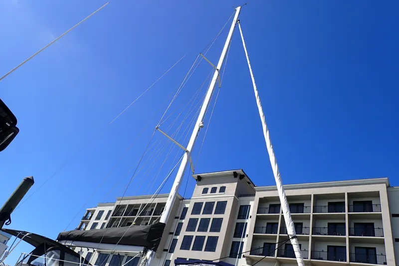 Slide: The Image of 2018 Jeanneau Sun Odyssey 389 sailboat mast against blue sky and modern building. - 17