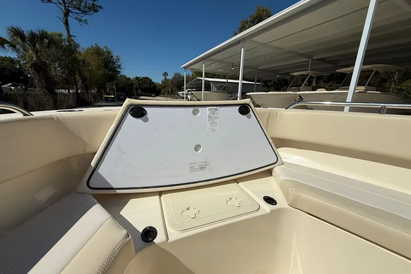 Slide: The Image of 2026 Scout 220 XSF boat interior with storage compartment, beige seating, and sunny outdoor setting. - 15