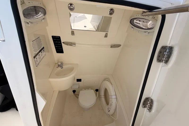 Slide: The Image of 2024 Cobia 262 Center Console boat interior with sink, toilet, and portholes. - 14