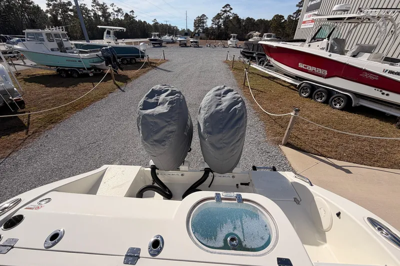 Slide: The Image of 2024 Cobia 262 Center Console boat with covered engines, parked in a marina. - 36
