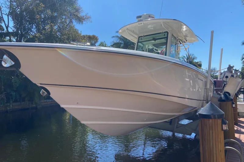 The Image of 2011 Boston Whaler 320 Outrage boat docked by a scenic waterfront. - 0