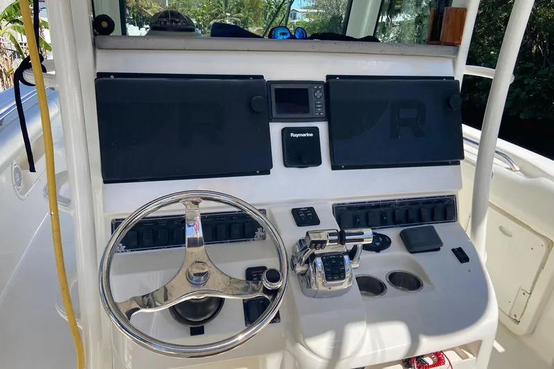 Slide: The Image of Control panel of a 2011 Boston Whaler 320 Outrage boat with steering wheel and electronics. - 2