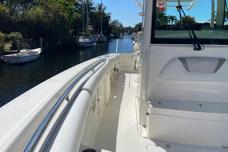 Slide: The Image of 2011 Boston Whaler 320 Outrage boat docked on a sunny day, surrounded by lush greenery. - 22