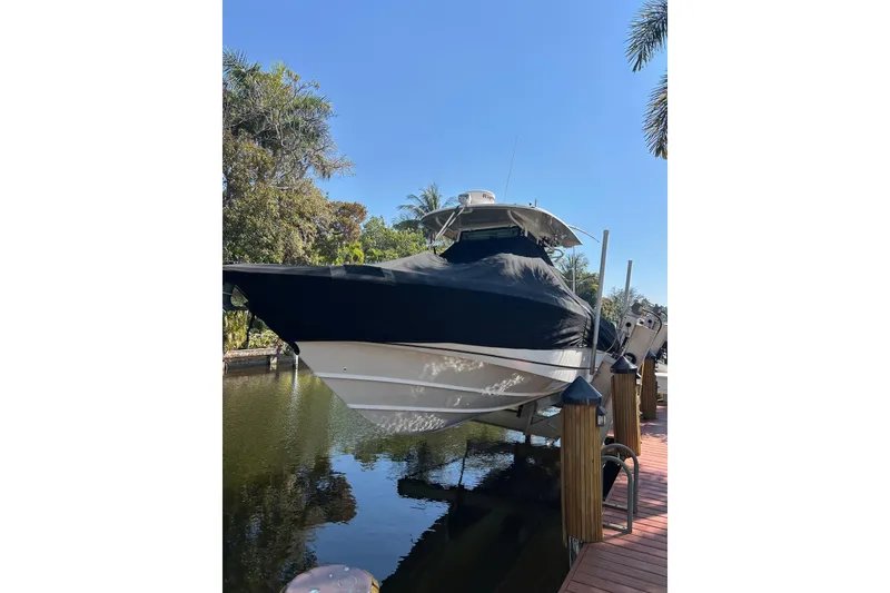 Slide: The Image of 2011 Boston Whaler 320 Outrage boat docked, covered, surrounded by tropical trees. - 35