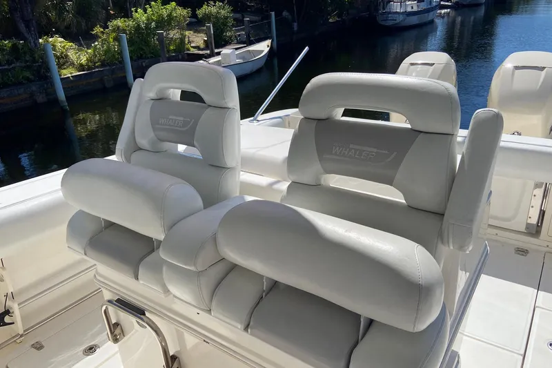Slide: The Image of 2011 Boston Whaler 320 Outrage boat seats, white leather, docked by water. - 5