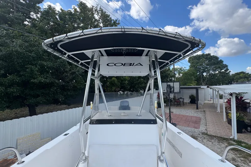 Slide: The Image of 2001 Cobia 254 Center Console boat with T-top, parked outdoors under blue sky. - 16