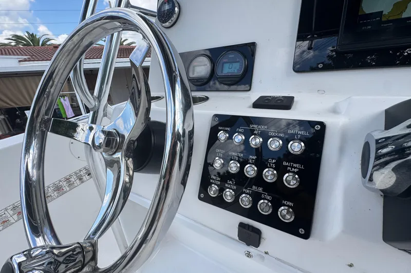 Slide: The Image of 2001 Cobia 254 Center Console boat dashboard with steering wheel and control panel. - 24