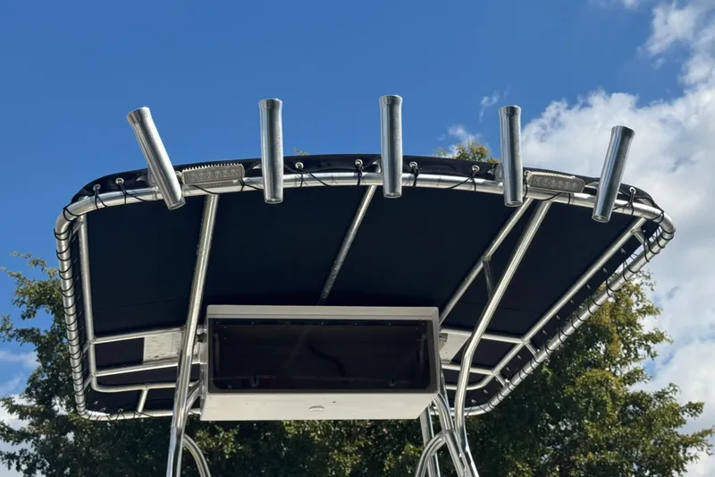 Slide: The Image of T-top of 2001 Cobia 254 Center Console boat with rod holders against blue sky. - 41